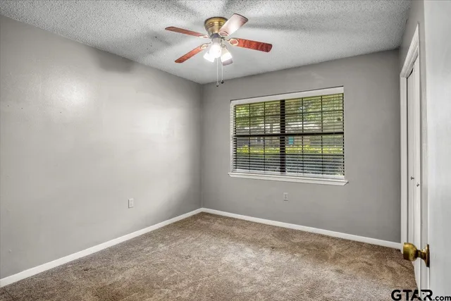 an empty room with a window and a ceiling fan
