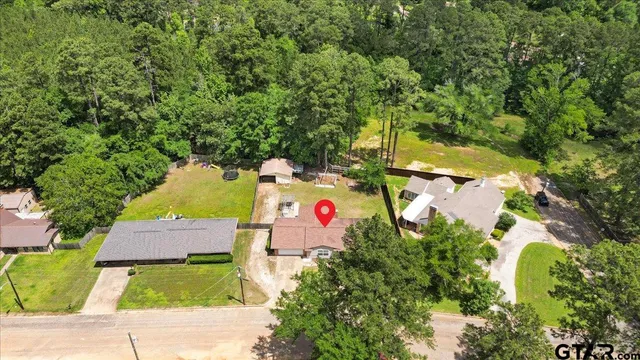 an aerial view of a house with swimming pool and large trees