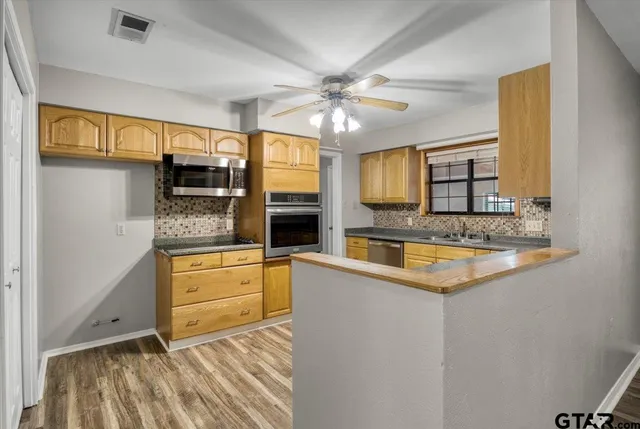 a kitchen with stainless steel appliances granite countertop a sink and dishwasher a stove with wooden floor