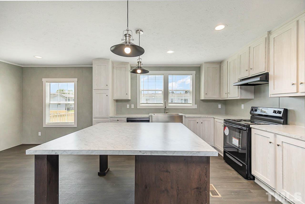 34 Ruddy Duck Lane Pine Level, NC 27576 - Photo 5 of 17 a kitchen with a stove a sink a kitchen island with chairs and cabinets