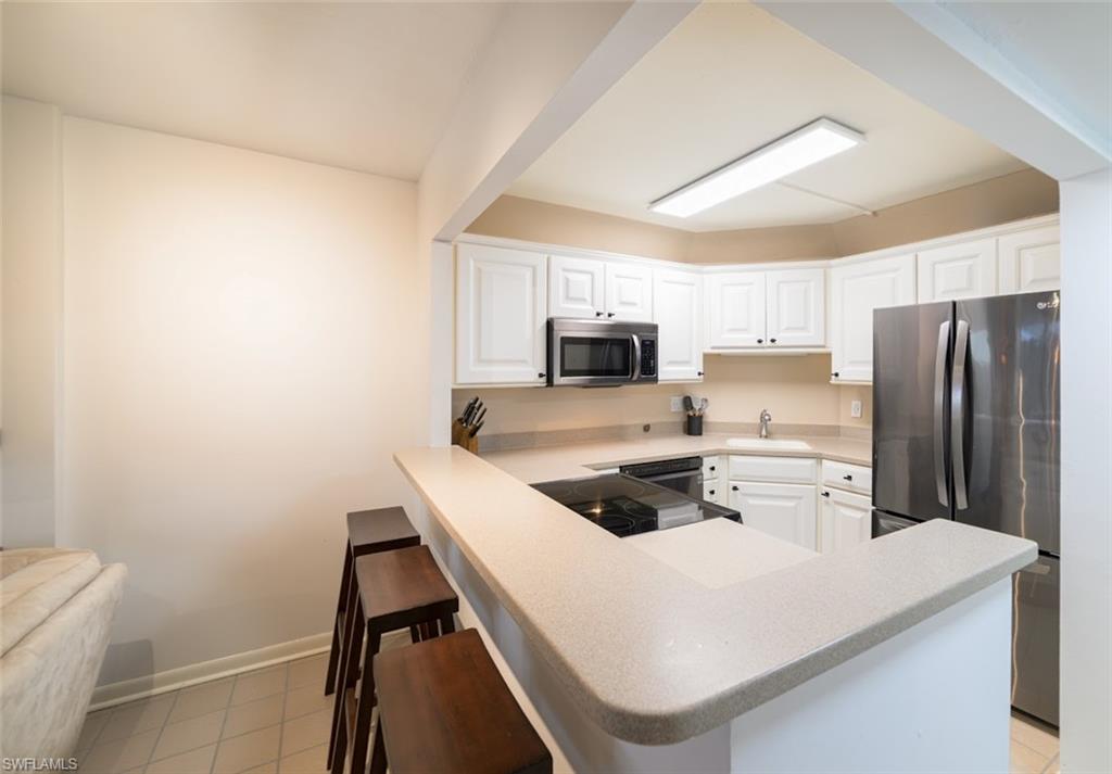 5 Bluebill Avenue, Unit 305 405 Naples, FL 34108 - Photo 13 of 30 a kitchen with cabinets and stainless steel appliances
