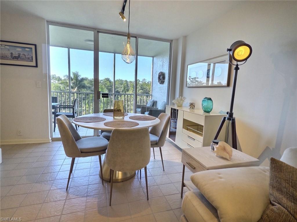 5 Bluebill Avenue, Unit 305 405 Naples, FL 34108 - Photo 6 of 30 a dining room with furniture a chandelier and wooden floor