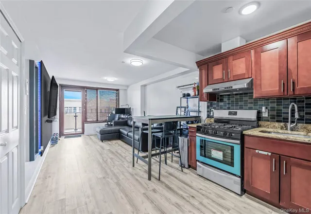 a kitchen with stainless steel appliances granite countertop a stove top oven a sink dishwasher a dining table and chairs with wooden floor