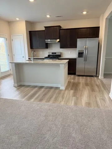 a kitchen with stainless steel appliances kitchen island granite countertop a sink a stove and a refrigerator