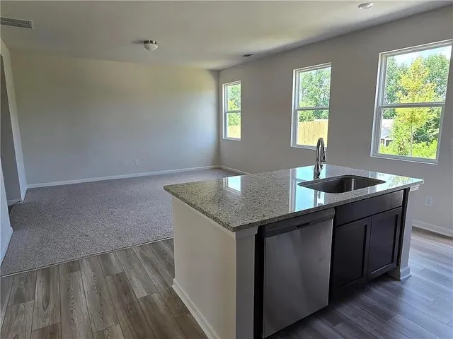 a kitchen with granite countertop a sink window and cabinets