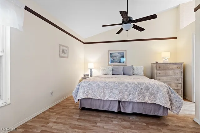 a bedroom with a bed and dresser with wooden floor