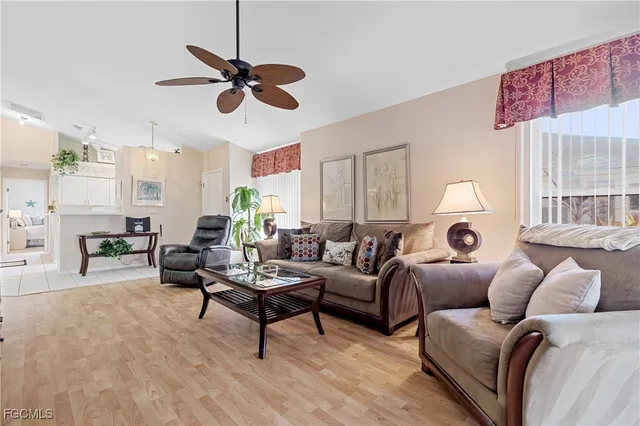 a living room with furniture a clock on a ceiling fan and a window