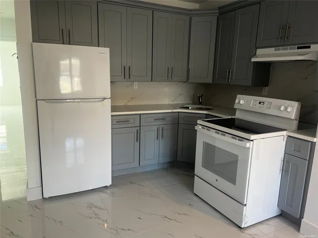 a white refrigerator freezer and a stove sitting inside of a kitchen with granite countertop
