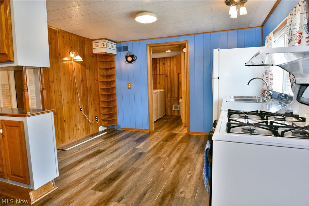 878 Ridge Road Vienna, OH 44473 - Photo 19 of 50 Kitchen with white appliances, dark wood-style flooring, wood walls, wood finish cabinets, and washer / clothes dryer