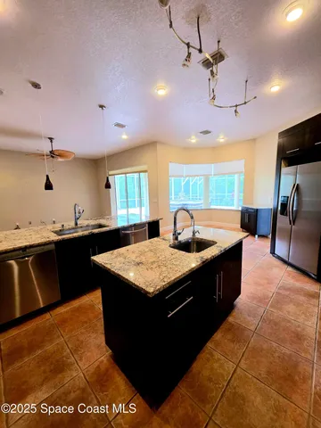 a kitchen with granite countertop a sink counter top space and stainless steel appliances