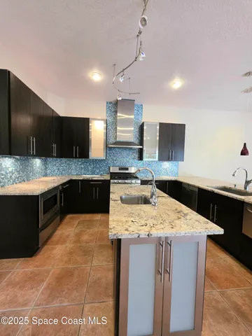 a large kitchen with a large counter top stainless steel appliances and cabinets