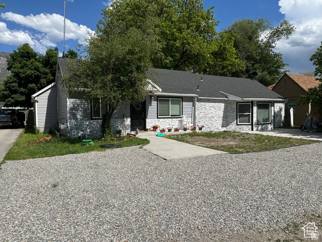 View of front of home featuring stone siding and roof with shingles