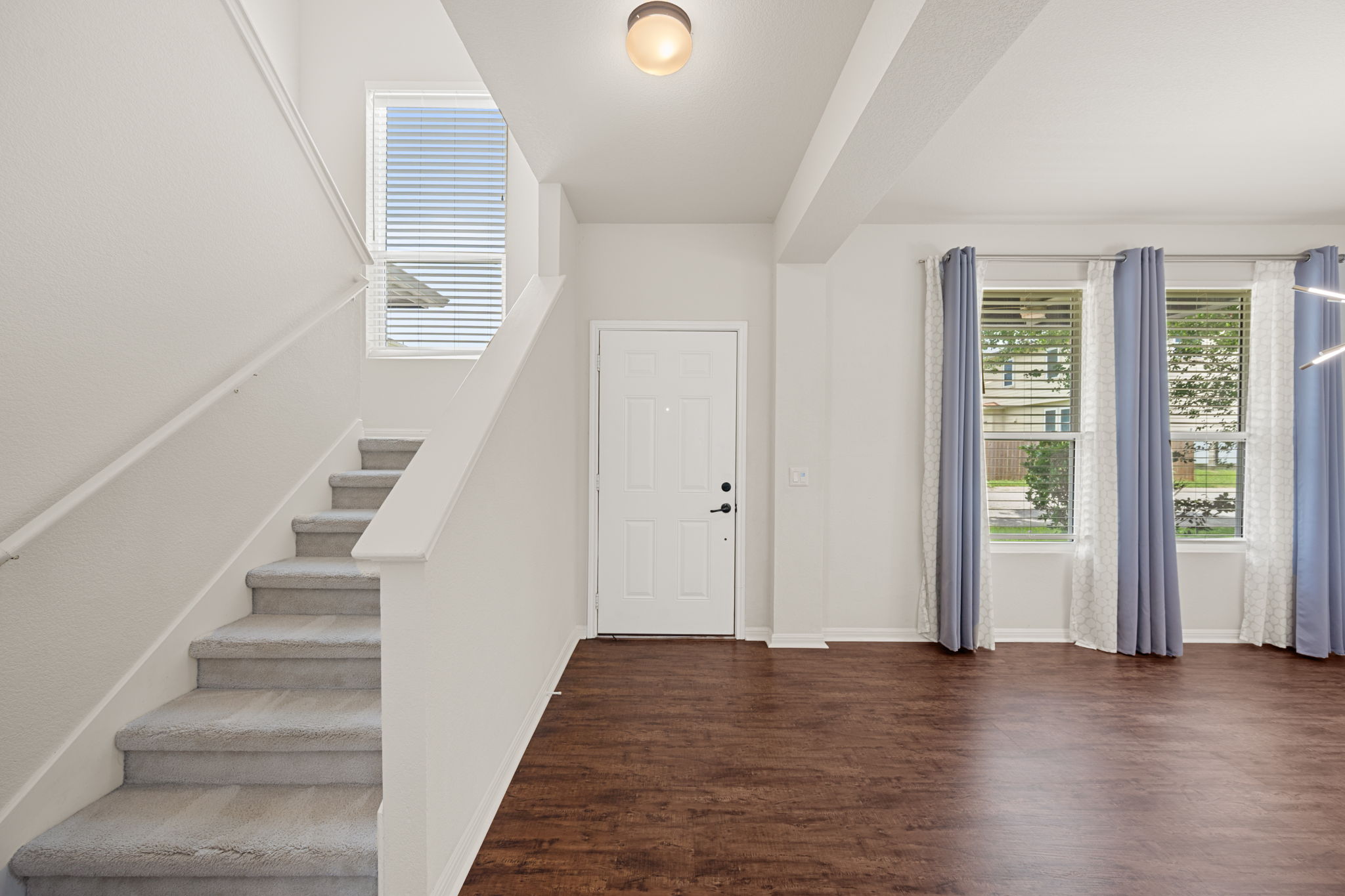 8902 Magna Carta Loop, Unit 122 Austin, TX 78754 - Photo 5 of 39 A welcoming entryway with a staircase leads to the main living area, featuring rich wood-look flooring.