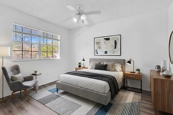 a view of a refrigerator in kitchen and an empty room with wooden floor