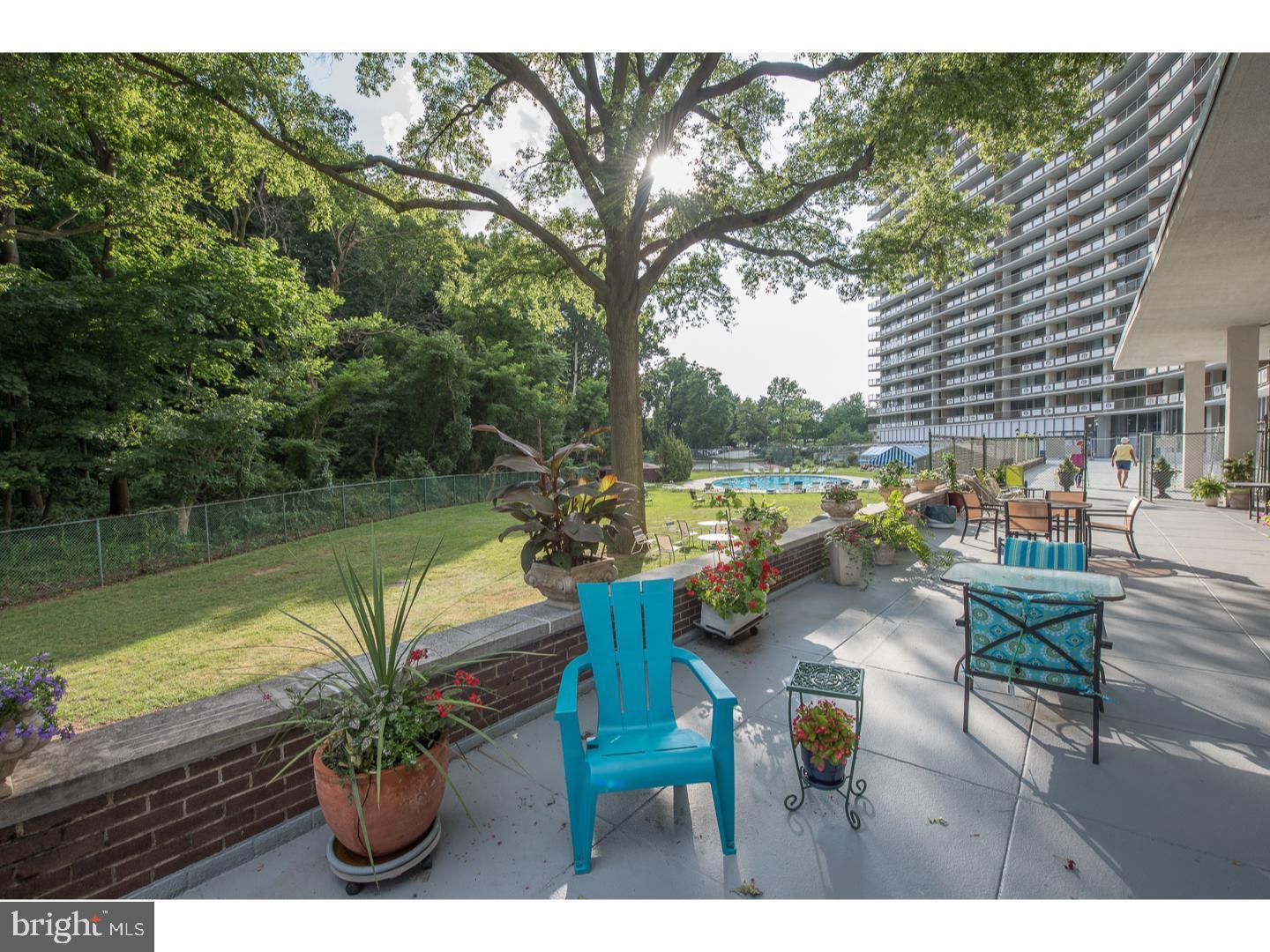 3900-00 West Ford Road, Unit 14K Philadelphia, PA 19131 - Photo 34 of 42 Serene patio with lush greenery backdrop.