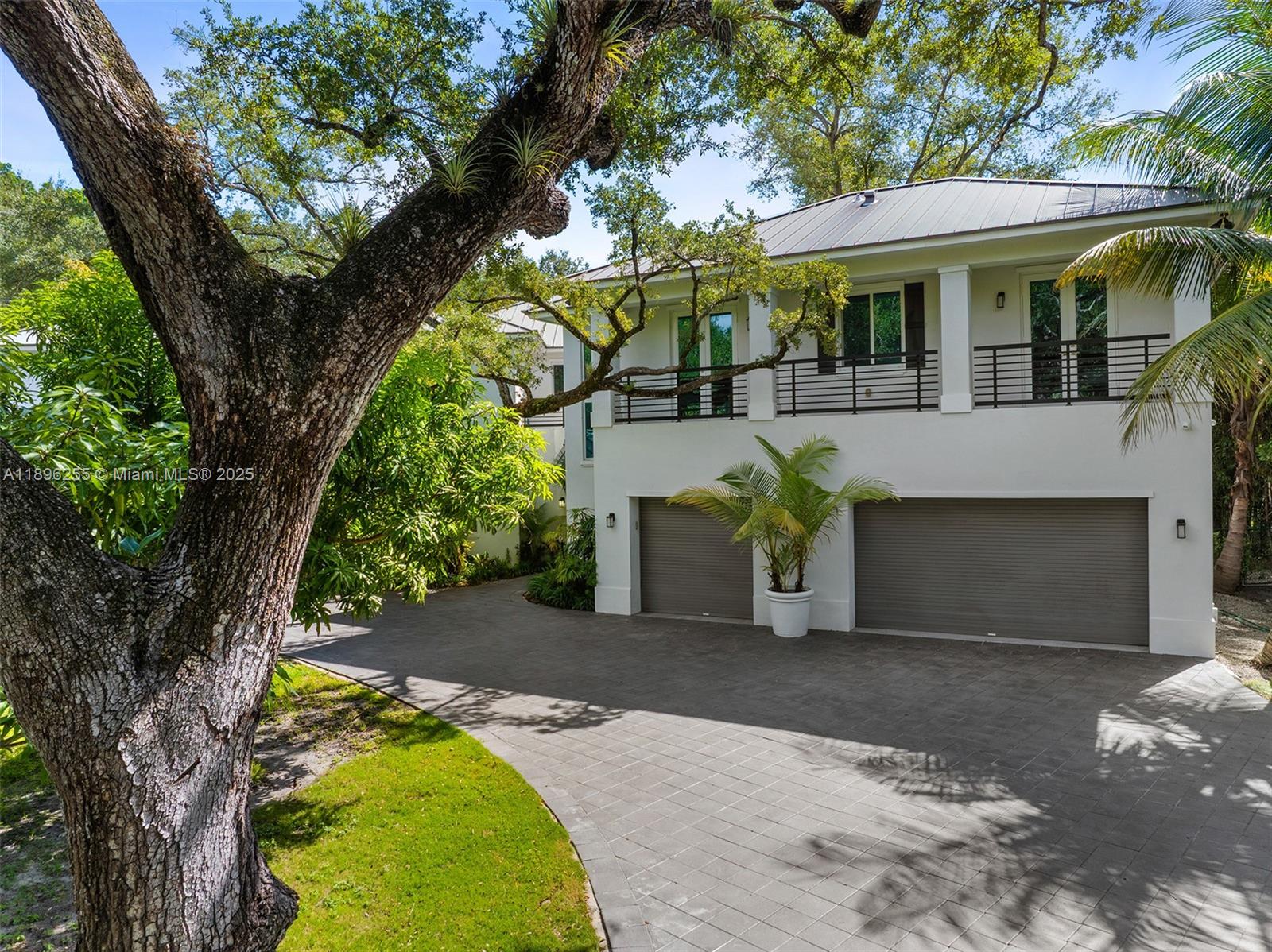 8923 Ludlam Road Pinecrest, FL 33156 - Photo 62 of 69 a view of a white house with large trees and a large tree