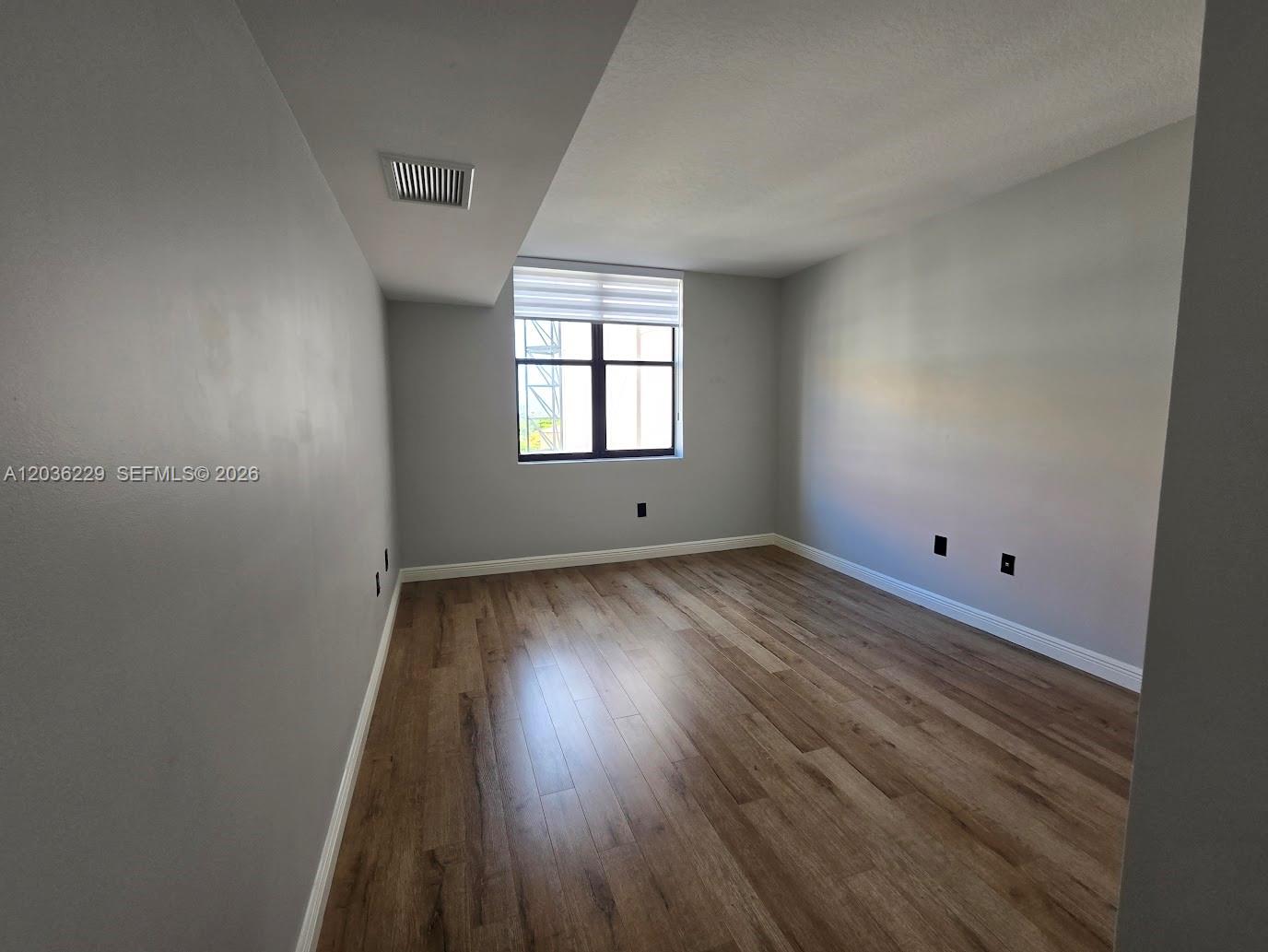 888 Douglas Road, Unit 605 Coral Gables, FL 33134 - Photo 16 of 21 an empty room with wooden floor and windows
