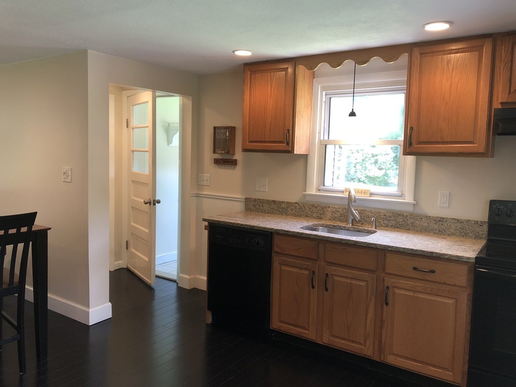 57 Middle Road Amesbury, MA 01913 - Photo 3 of 20 a kitchen with a sink a window a refrigerator and wooden cabinets