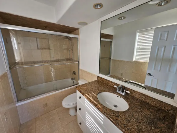 a bathroom with a granite countertop sink toilet and shower