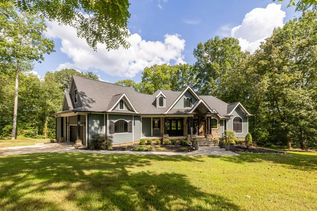 a front view of a house with a garden and trees