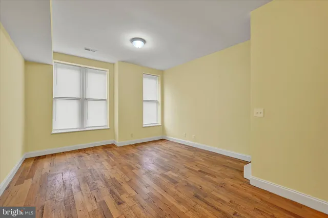 an empty room with wooden floor and windows