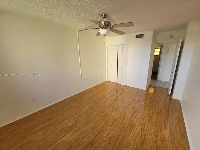 a view of a room with wooden floor and a ceiling fan