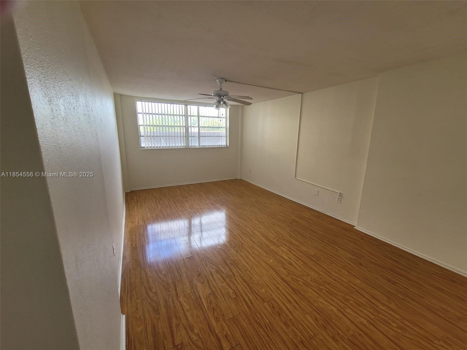 16400 Northeast 17th Avenue, Unit 206 North Miami Beach, FL 33162 - Photo 8 of 12 an empty room with wooden floor and windows