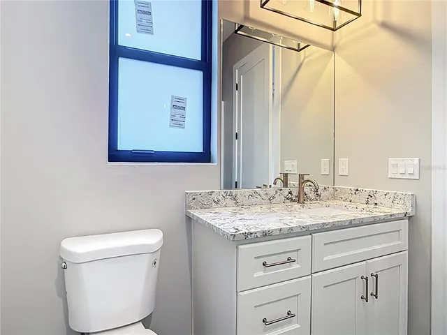 a bathroom with a granite countertop sink toilet and mirror