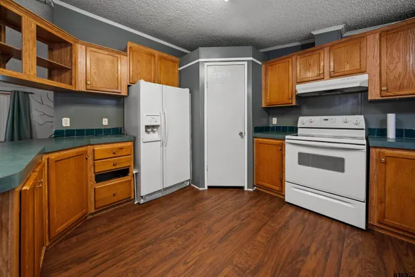 a kitchen with stainless steel appliances granite countertop a refrigerator a stove top oven and wooden floors