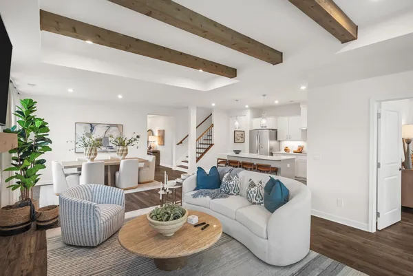 a living room with furniture and a dining table with wooden floor