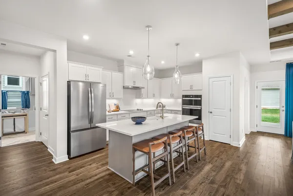 a kitchen with stainless steel appliances a refrigerator a stove a sink dishwasher and a dining table with wooden floor