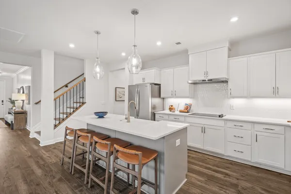 a kitchen with stainless steel appliances kitchen island granite countertop a table chairs and a refrigerator