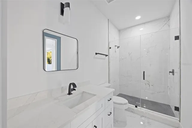 a bathroom with a toilet a sink a mirror and shower