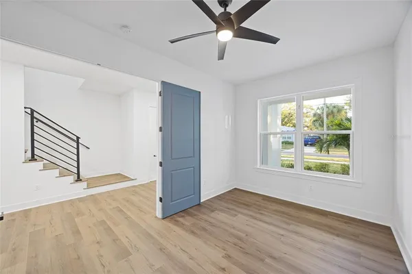 an empty room with wooden floor fan and windows