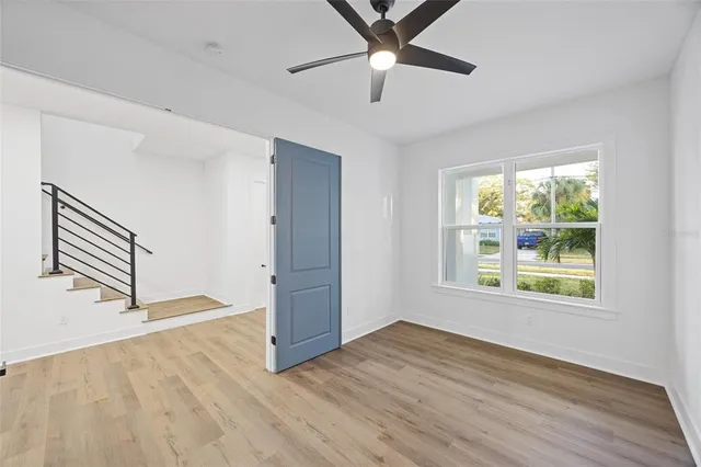 an empty room with wooden floor fan and windows