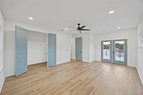 an empty room with wooden floor ceiling fan and windows