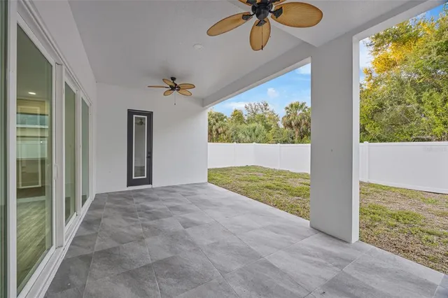 an empty room with wooden floor and fan