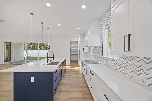 a large kitchen with kitchen island a sink stove and wooden floor