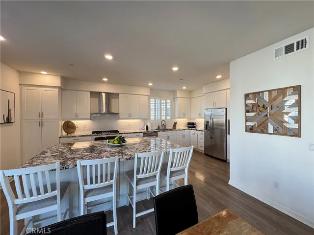 a kitchen with stainless steel appliances granite countertop a stove a refrigerator a kitchen island with a dining table and chairs