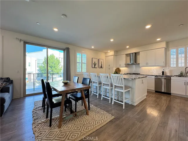 a kitchen with stainless steel appliances granite countertop a table chairs sink and wooden floor