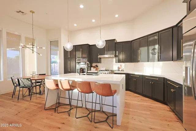 a large kitchen with kitchen island granite countertop a dining table chairs and white cabinets