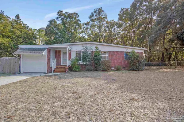 front view of a house with potted plants and large trees