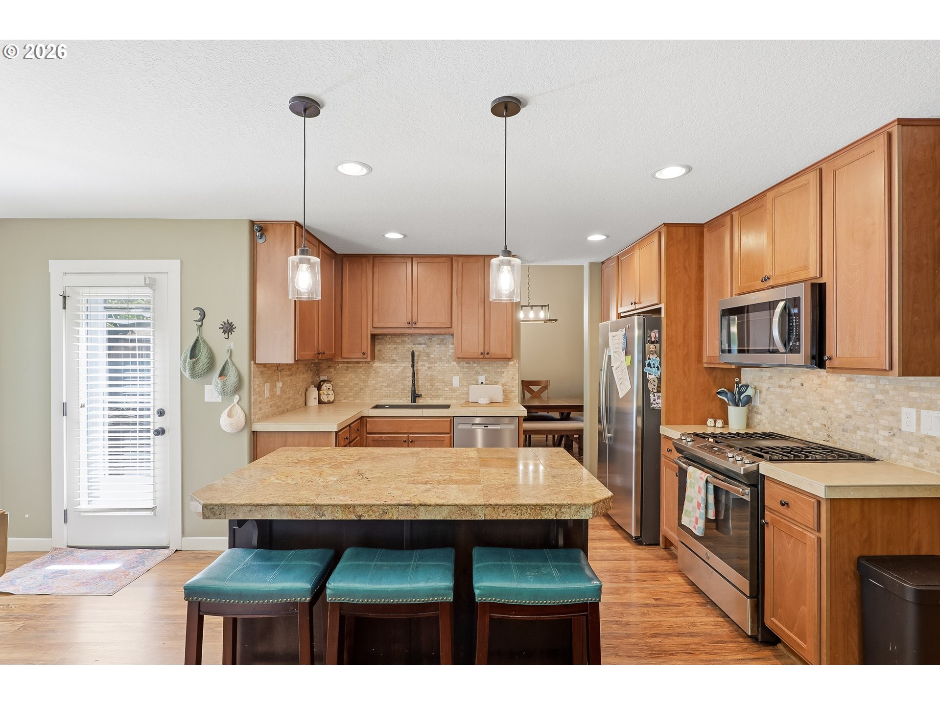 17376 Aubin Street Sandy, OR 97055 - Photo 8 of 21 a kitchen with kitchen island granite countertop a stove a sink a refrigerator and chairs
