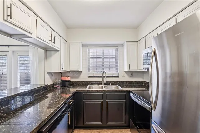 a kitchen with granite countertop a refrigerator stove and sink