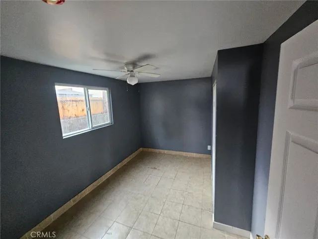 an empty room with windows and fan