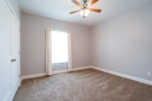 an empty room with closet and a chandelier fan