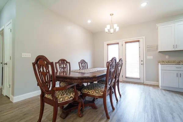 a dining room with furniture a chandelier and wooden floor