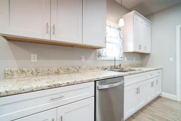 a kitchen with granite countertop white cabinets and a sink