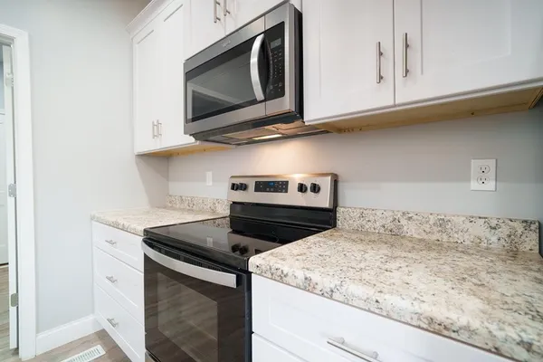 a kitchen with granite countertop cabinets stainless steel appliances and a wooden floor