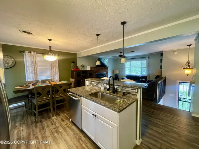 a kitchen with kitchen island granite countertop a sink a counter top space and stainless steel appliances